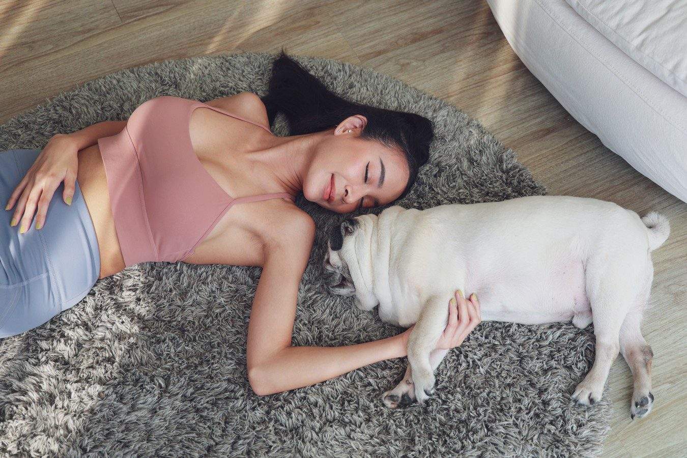 jeune femme avec son chien pug sur un tapis